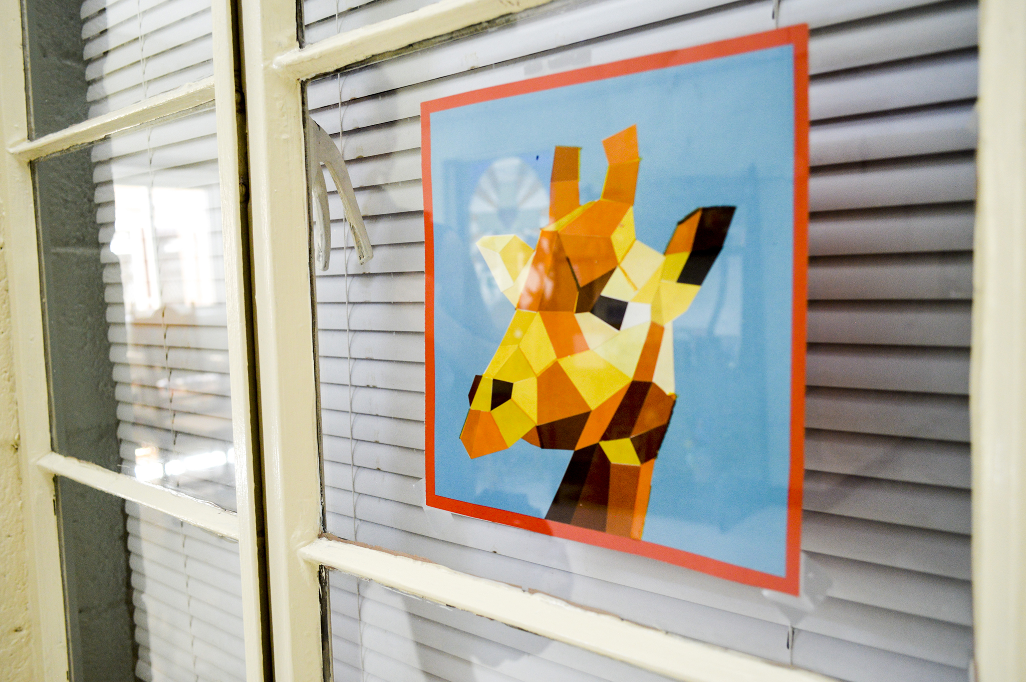 A giraffe mosaic art piece made by Gloria’s youngest daughter hangs  is shown in the window of Gloria’s room.