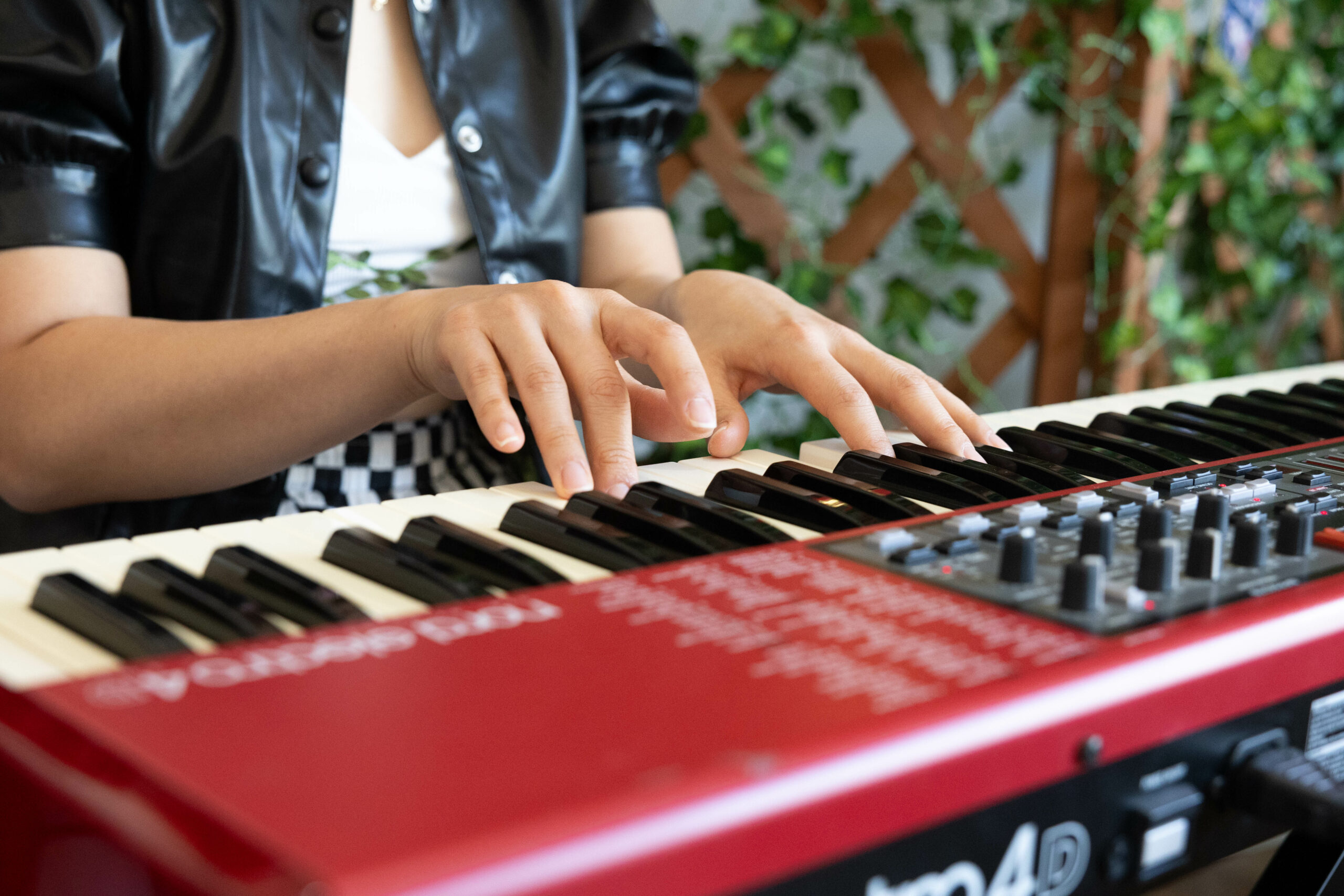 A close-up shot of Promqueen’s hands while playing a red piano keyboard.
